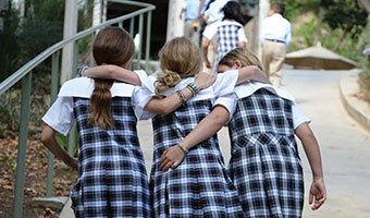 children in school uniforms walking with arms around each other